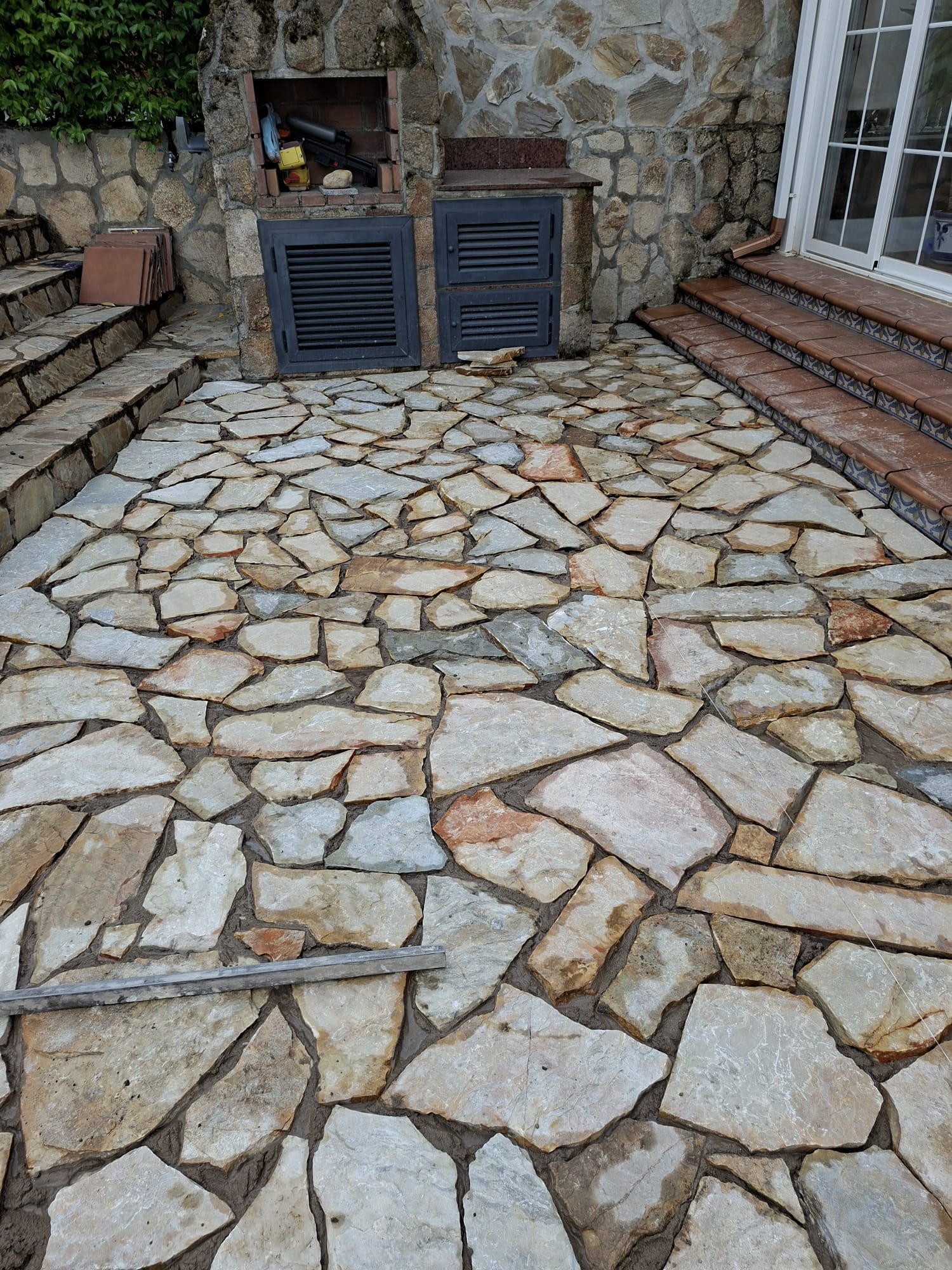 Terraza junto a piscina después de la reforma, con suelo de piedra natural